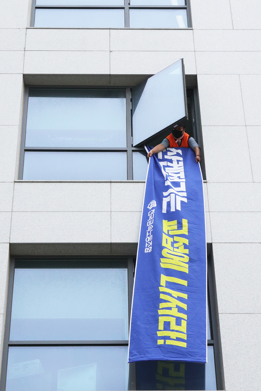 6월 22일 사흘째 서울 강서구 마곡동 APTC 점거농성 중인 한국산연지회 조합원이 산켄전기 직접교섭을 촉구하는 현수막을 건물 외벽에 내걸고 있다. 신동준