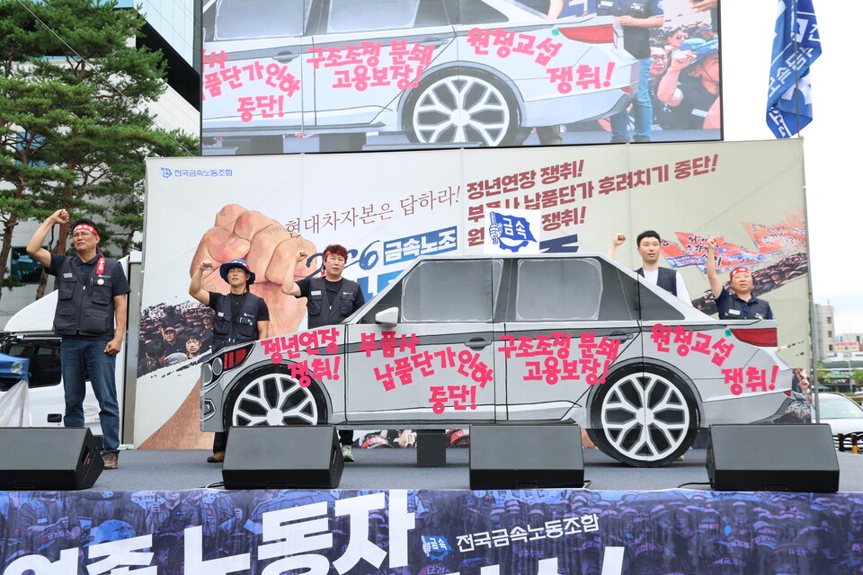 21일 오후 양재동 현대자동차 본사 앞에서 열린 ‘현대차그룹 정년 연장 쟁취! 부품사 납품단가 후려치기 중단! 원청교섭 쟁취! 금속노조 자동차 업종 공동 파업 대회’ 참가자들이 완성차, 부품사, 하청 노동자들이 함께 만든 자동차를 의미하는 상징 의식을 펼치고 있다. 사진=서지효 선전홍보부장